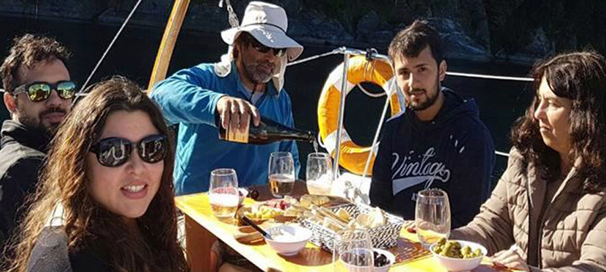 Grupo de viajeros disfrutando un momento de relax con infusiones calientes a bordo de un velero de Diversidad. Turismo Activo & de Naturaleza en el Brazo Campanario del Lago Nahuel Huapi, Bariloche