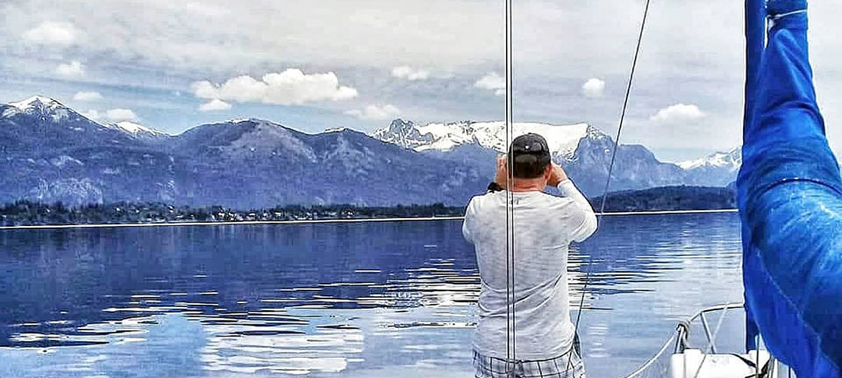 Viajeros timoneando un velero durante una experiencia náutica auténtica en el Brazo Campanario, Lago Nahuel Huapi, Bariloche, con Diversidad. Turismo Activo & de Naturaleza